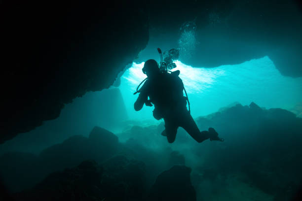 One scuba diver going deeper in underwater cave.